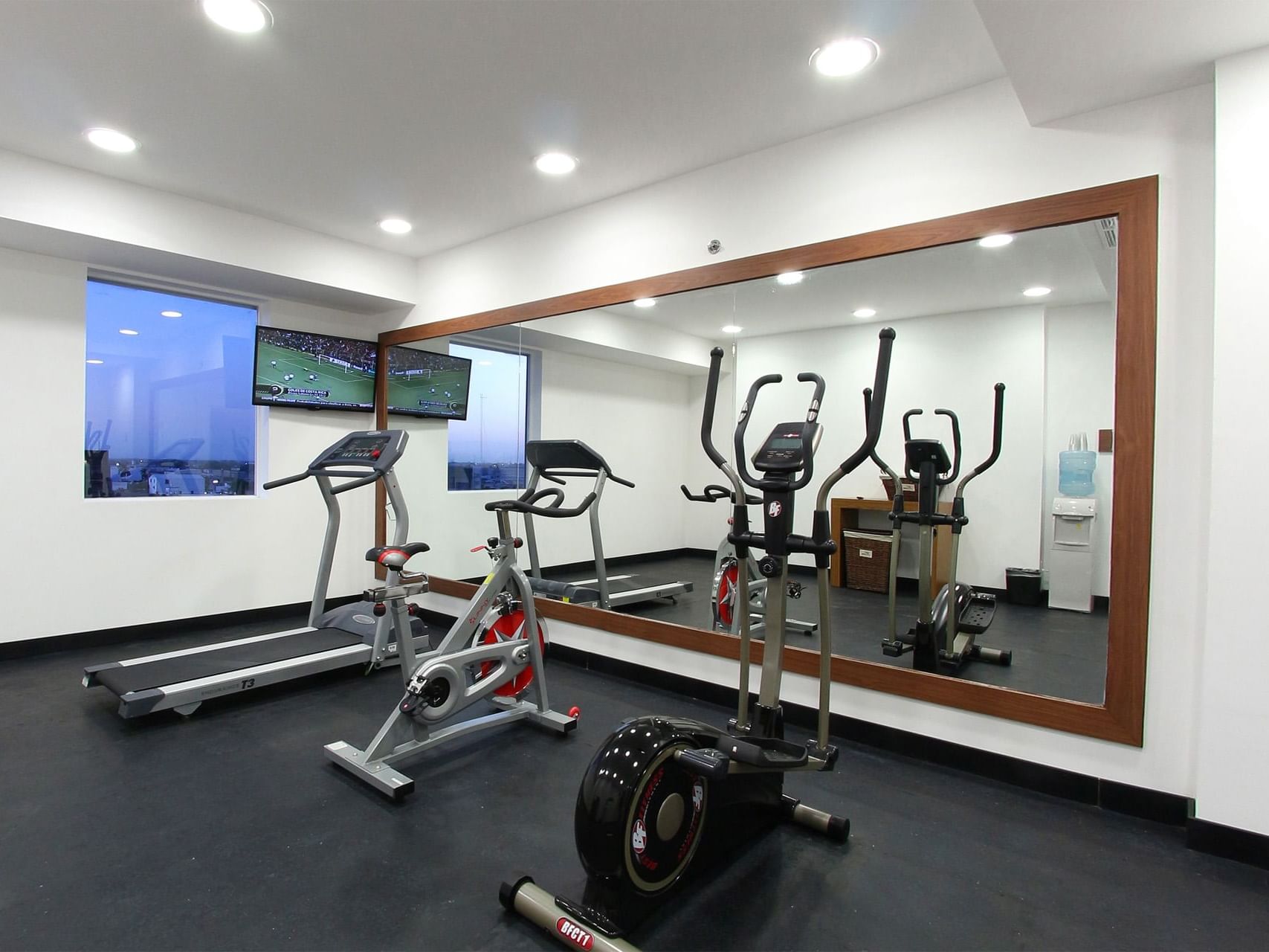 Exercise machines facing a big wall mirror in a gym, One Hotels