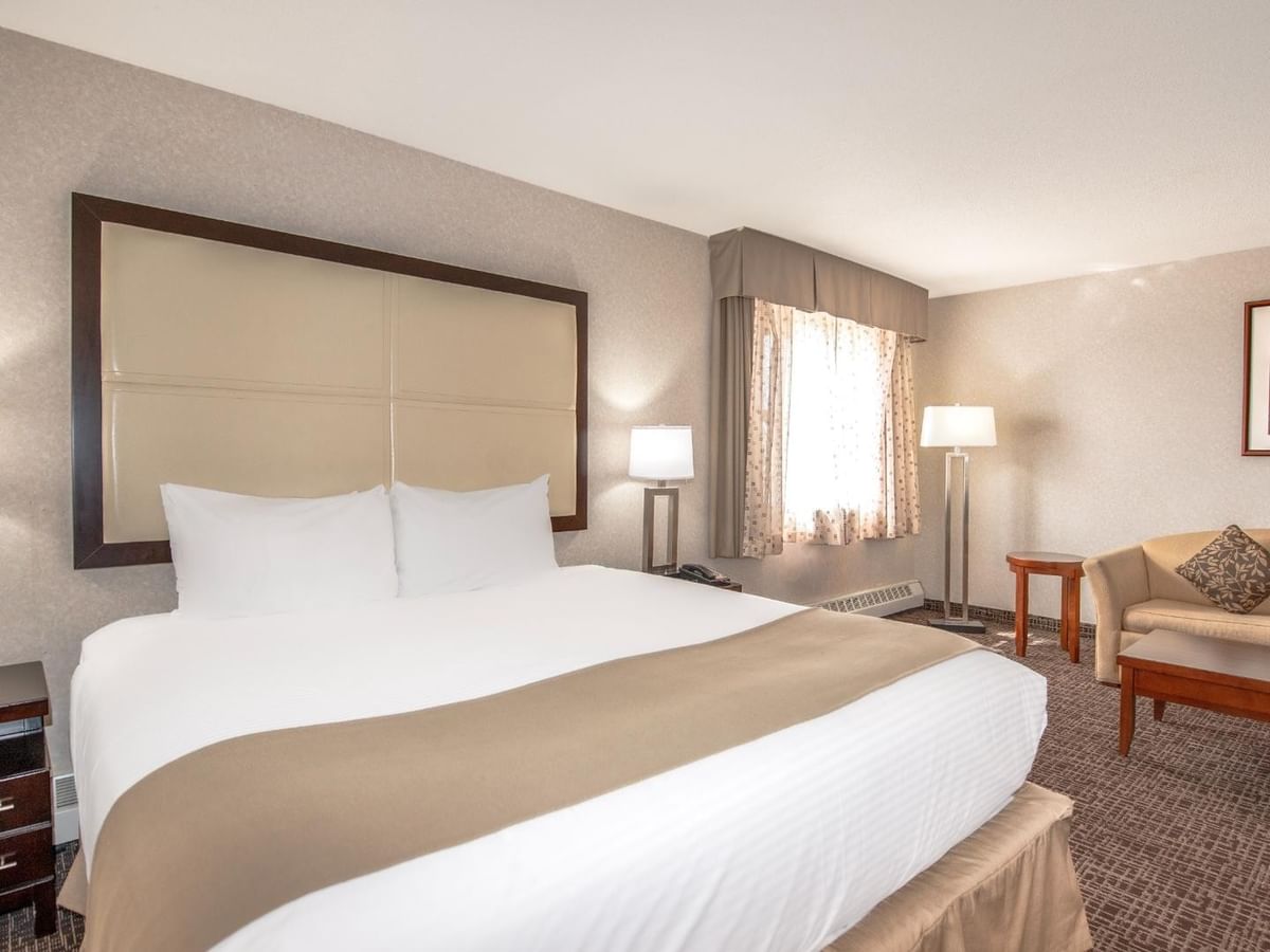 A hotel room with a king bed, two couches, a coffee table, and a framed artwork.