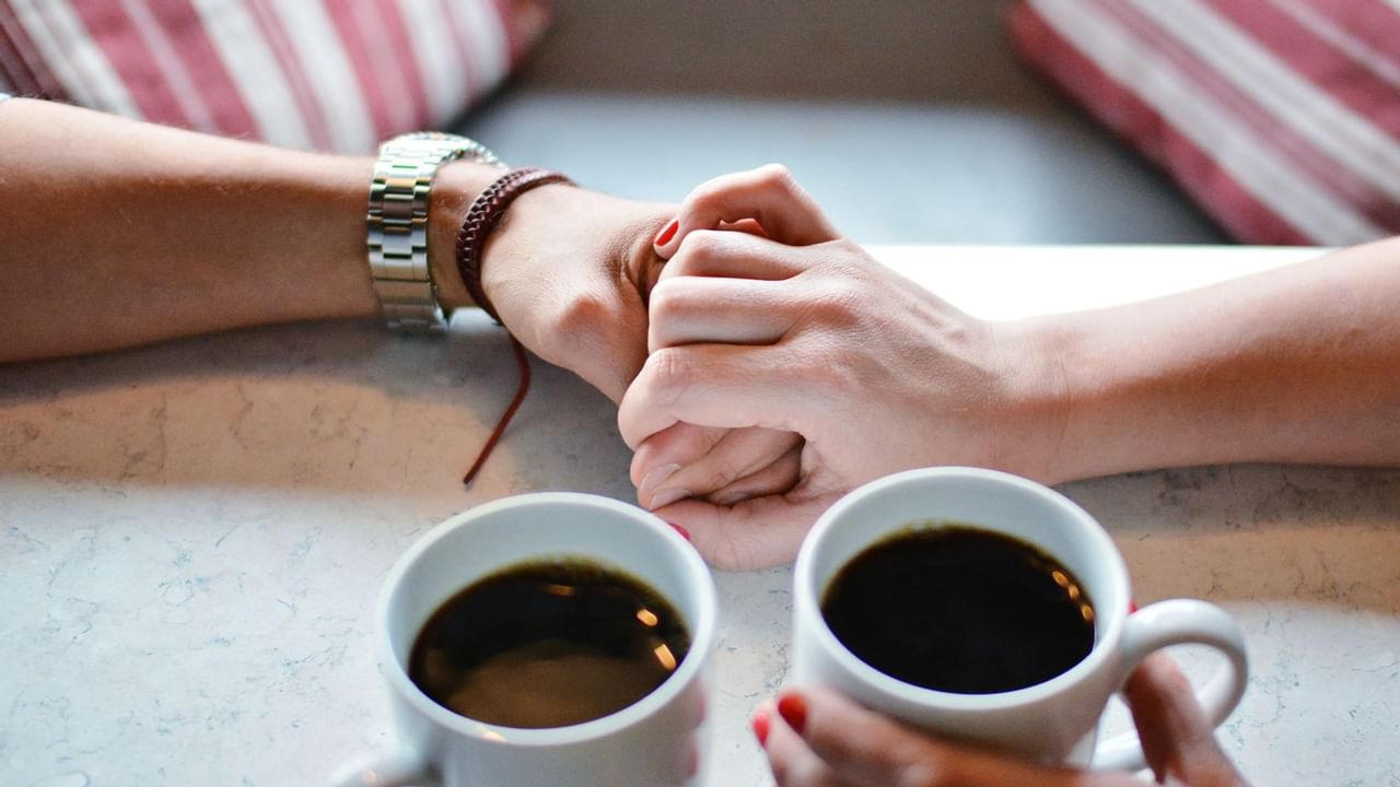 Couple holding hands with two cups of coffee