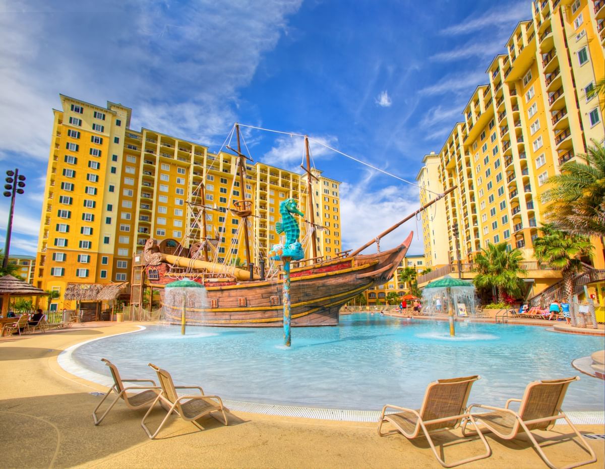 A large outdoor pool with a pirate ship water feature and lounge chairs.