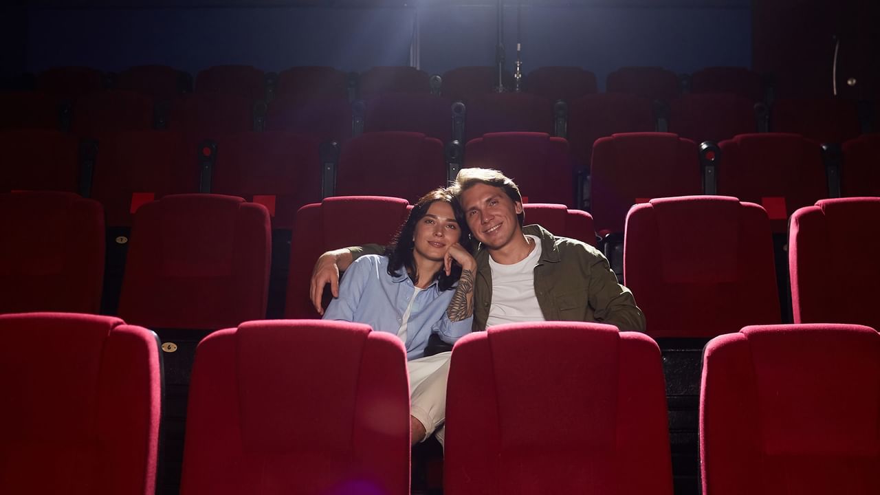 Couple smiling and sitting in the cinema.
