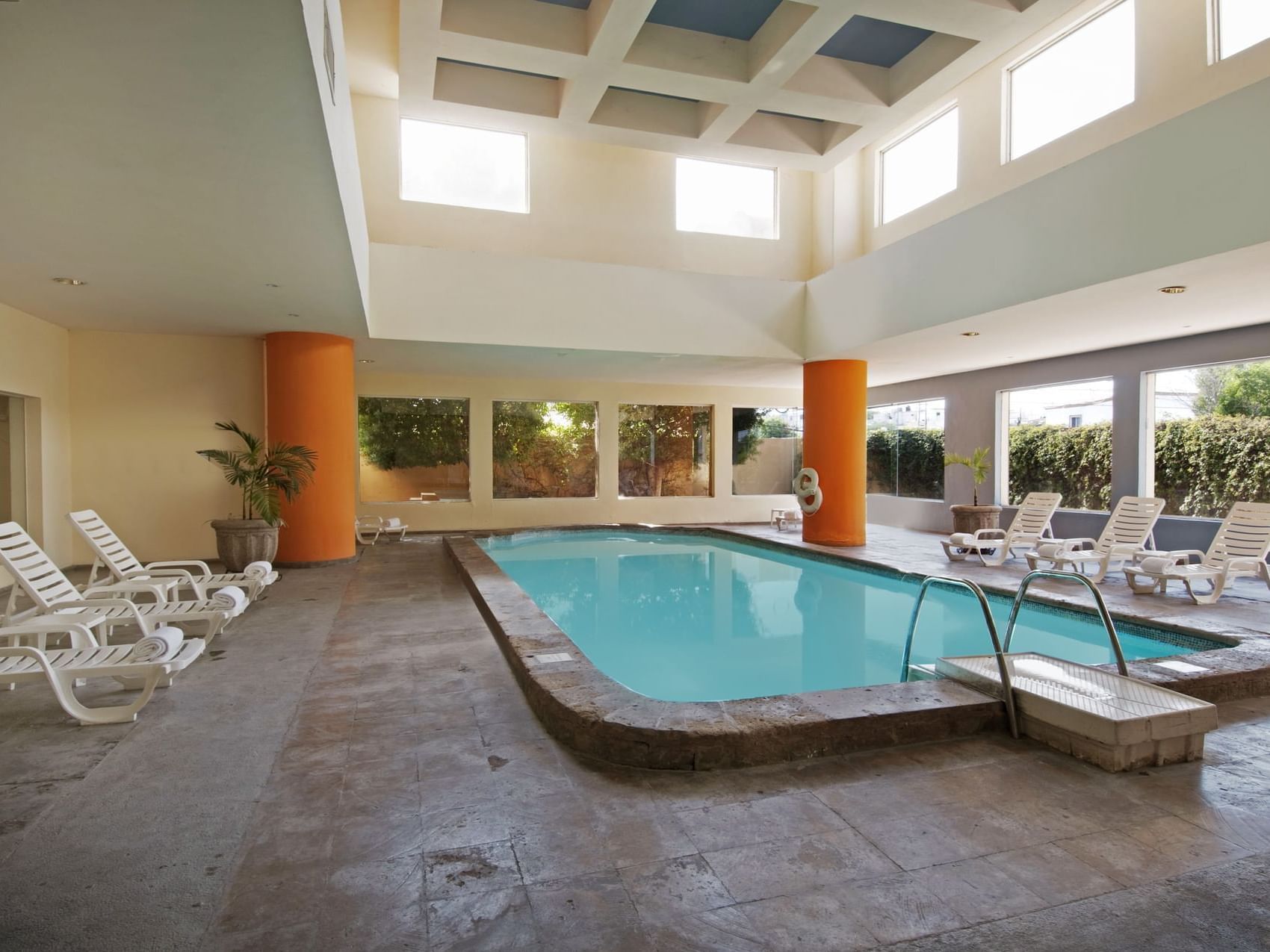 Indoor swimming pool with pool chairs at Fiesta Inn Hotels
