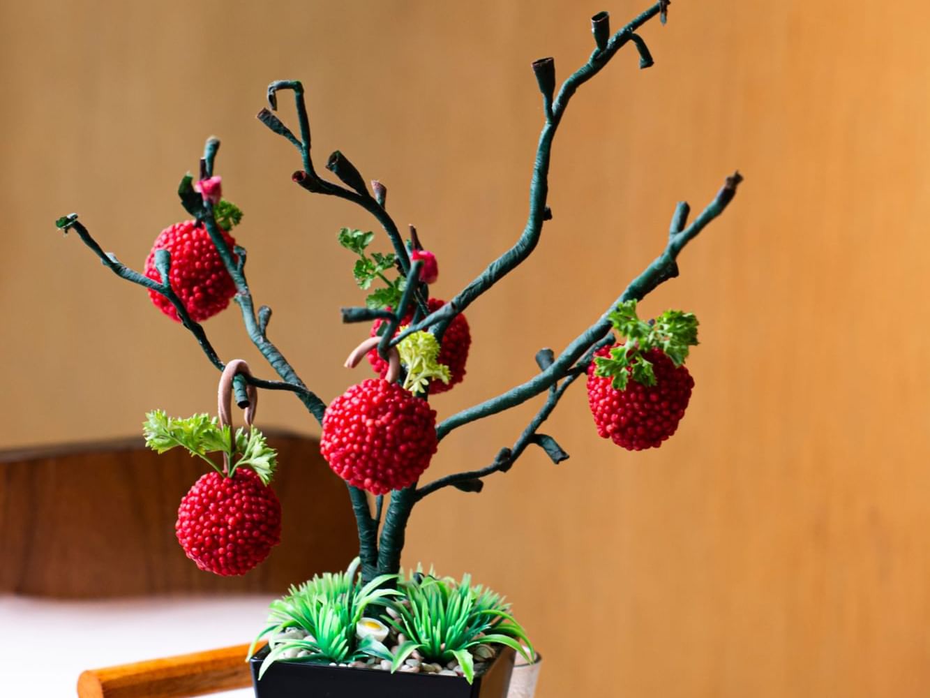 A decorative artificial tree with red fruit resembling strawberries and green leaves at Vasa Hotel Surabaya