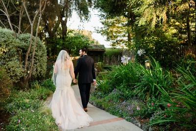 Bride and groom holding hands walking through a garden