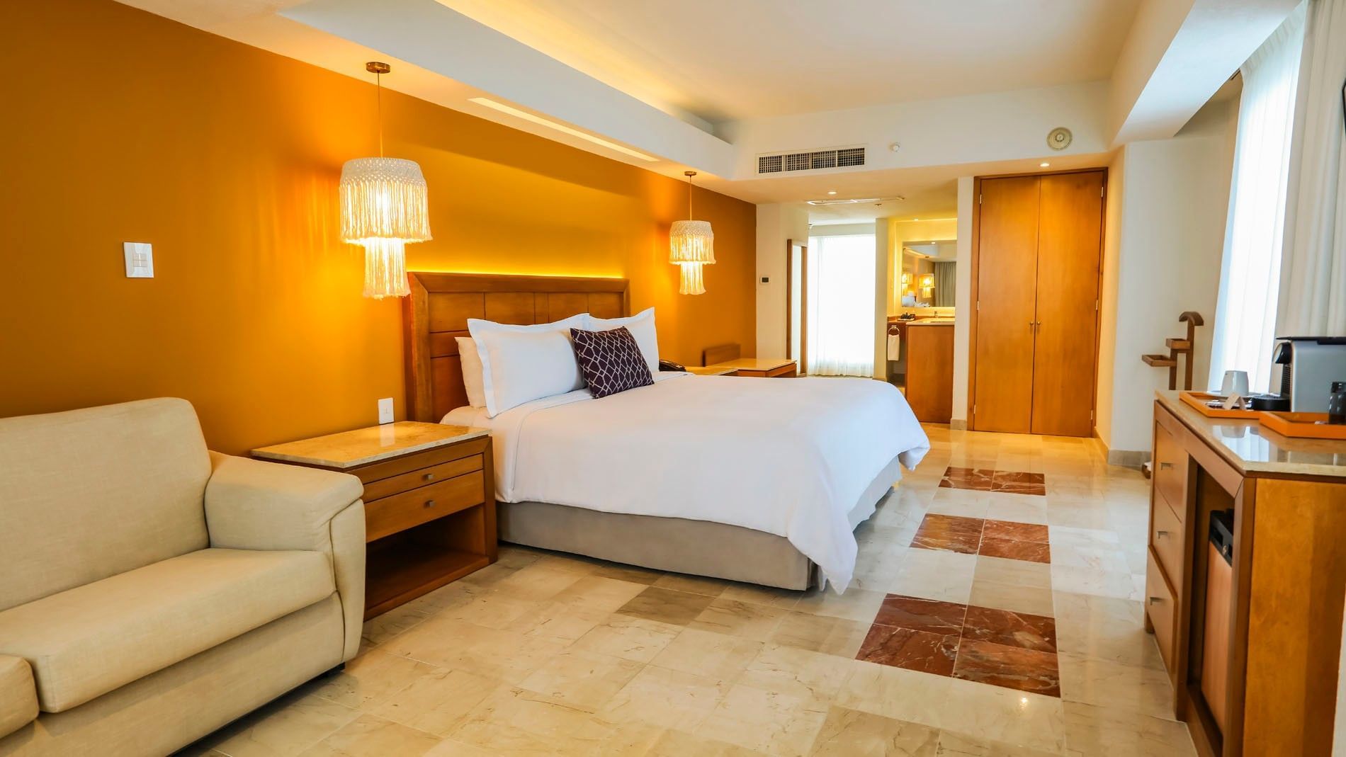 Wide shot of a King Junior Suite with a lounge sofa and a glimpse into the modern bathroom area at Camino Real Veracruz