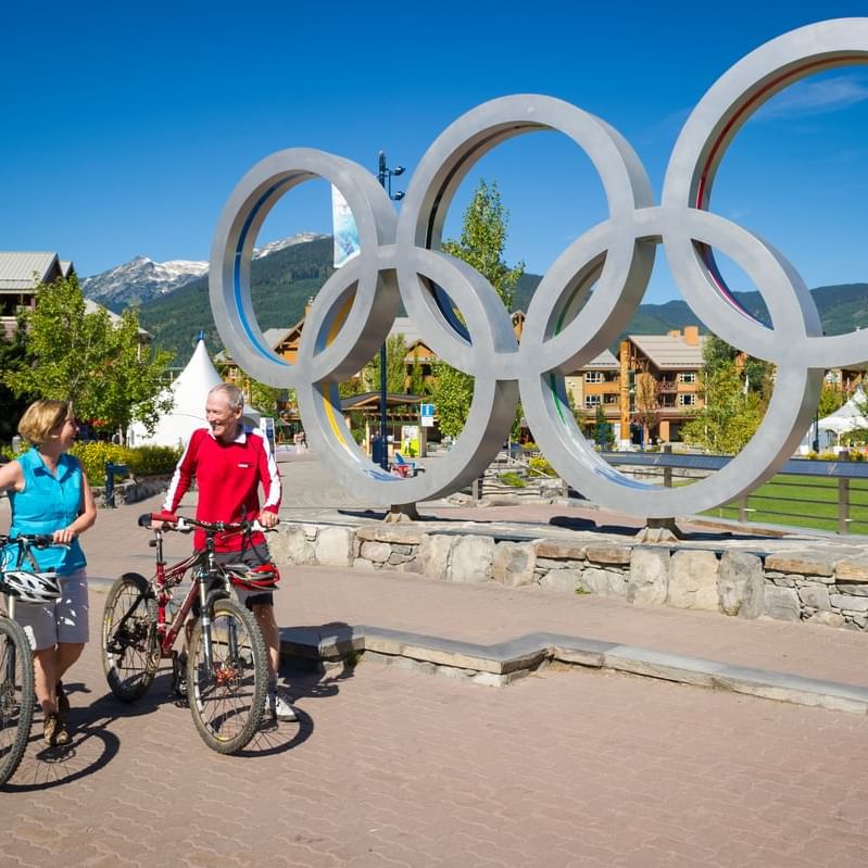 Two cyclists by the Whistler Olympic Rings Alamy near Blackcomb Springs Suites