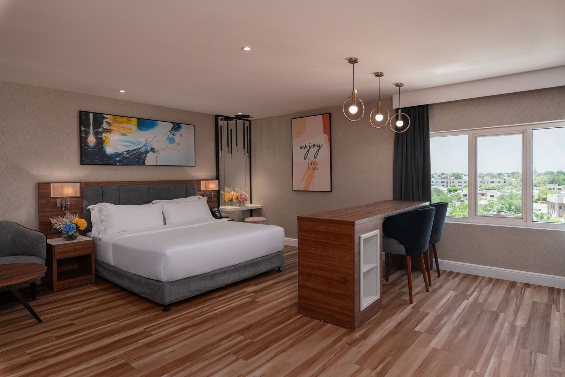 King bed by a tall wooden bar table and two chairs in Executive Room City View at Warwick Al Jubail