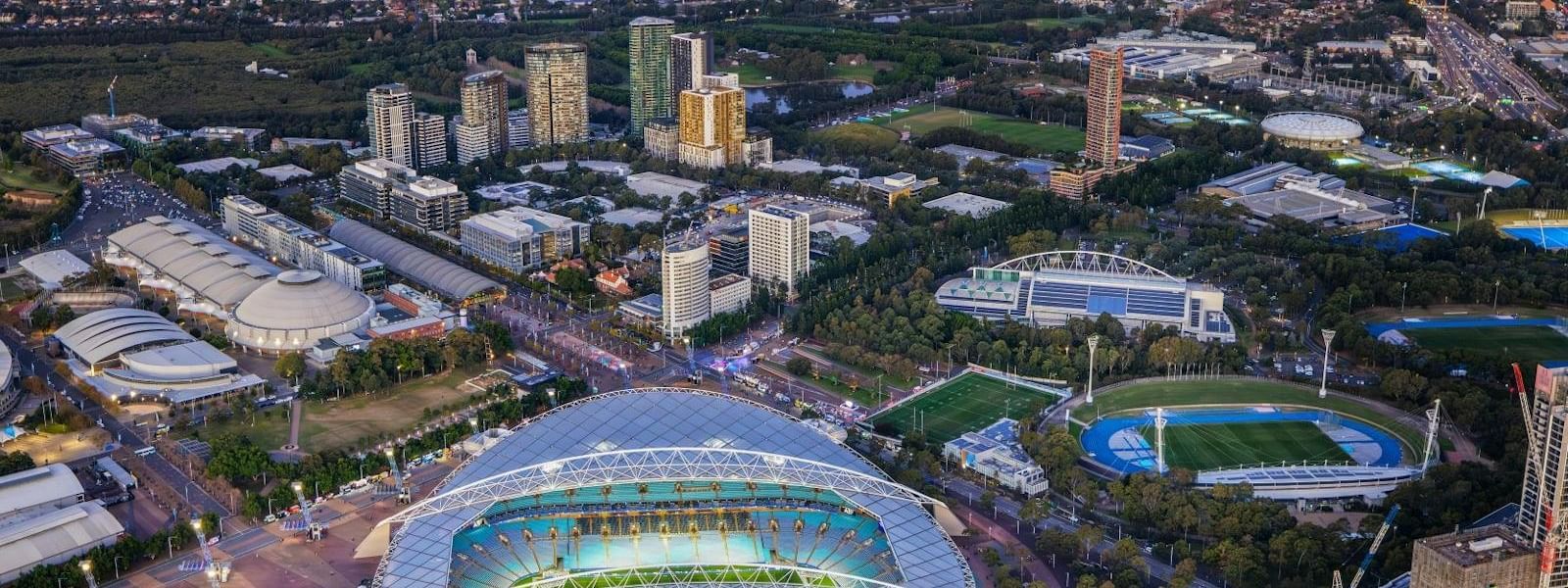 Aerial view of Sydney Olympic Park with stadium and surrounding urban landscape.