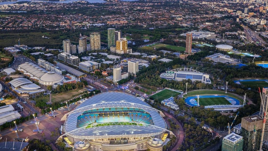 Aerial view of Sydney Olympic Park with stadium and surrounding urban landscape.