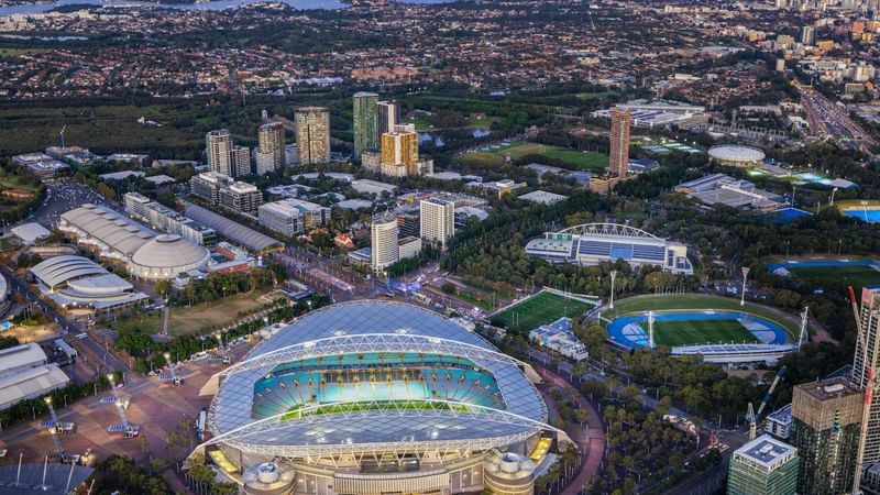 Aerial view of Sydney Olympic Park with stadium and surrounding urban landscape.