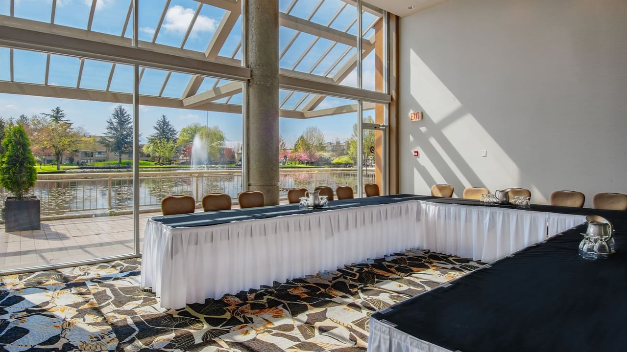 Indoor conference room with long tables, chairs, and a view of a pond.