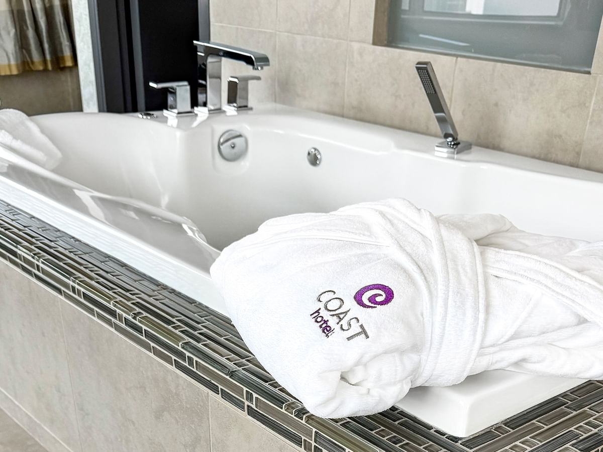 Coast Carrie Cates Penthouse Suite bathtub and a white robe at Coast Lonsdale Quay Hotel