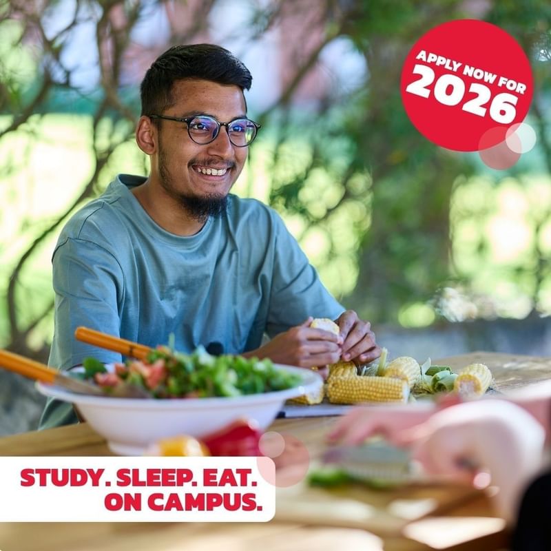 Man preparing food at a table with text: Apply now for 2026, Study. Sleep. Eat. On campus.