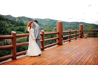 A bride & a groom posing on a deck at Stein Eriksen Lodge