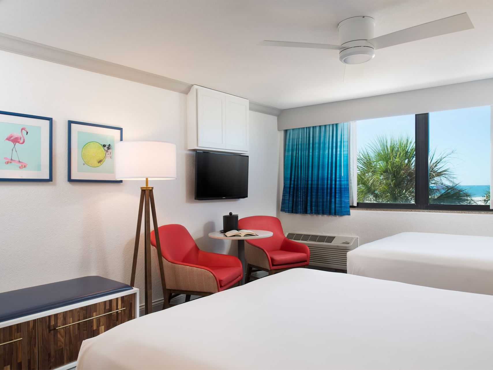 two beds facing two red chairs