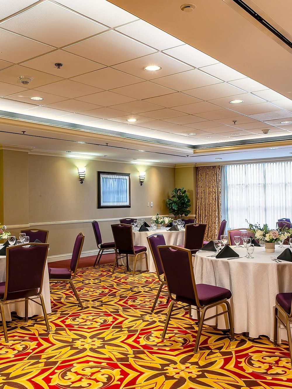 Set tables with purple chairs by patterned carpet under warm wall lights in Capitol IV at Warwick Denver