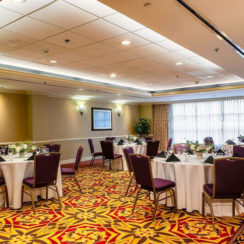 Set tables with purple chairs by patterned carpet under warm wall lights in Capitol IV at Warwick Denver
