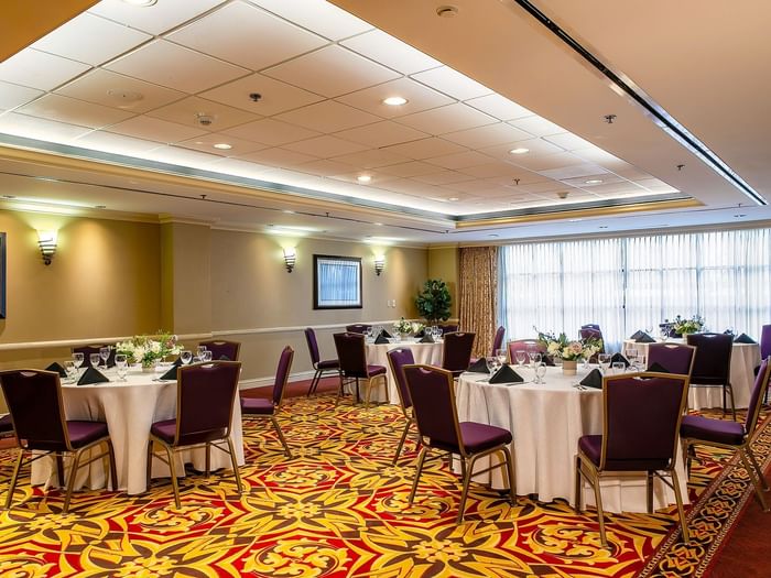 Set tables with purple chairs by patterned carpet under warm wall lights in Capitol IV at Warwick Denver