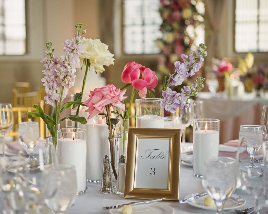 Table setting with pink flowers, white candles, and a table number card in the banquet hall at Warwick Allerton Chicago
