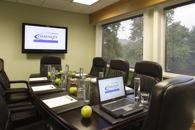 Conference room with black leather chairs, notepads, and wall-mounted screen at Aramark Chauncey Conference Center