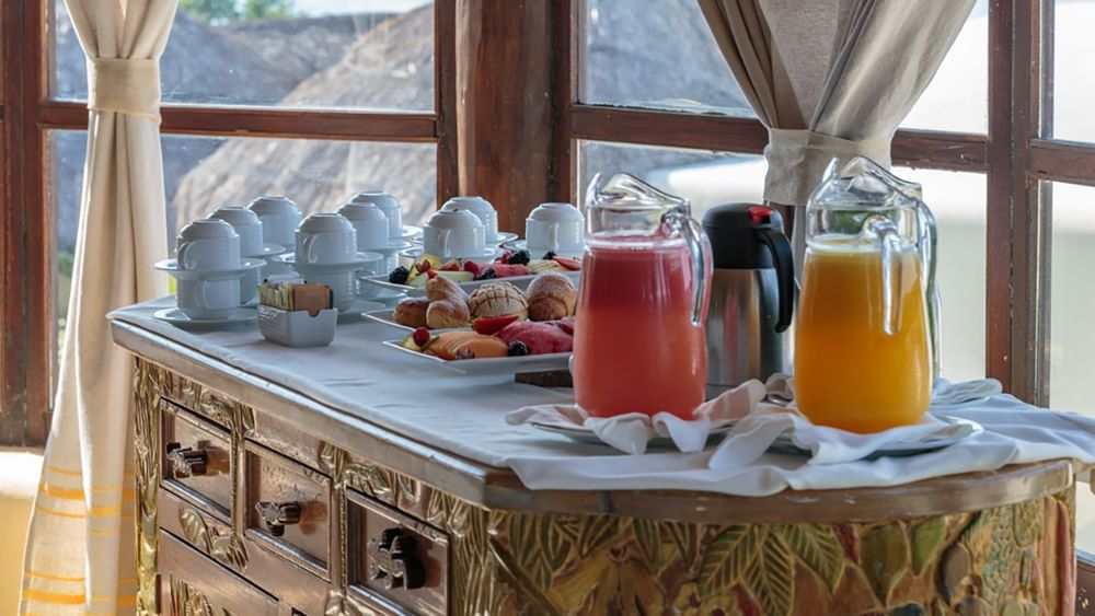 Juice pitchers and coffee cups on a carved wooden sideboard by a window served at Quinta Real Huatulco