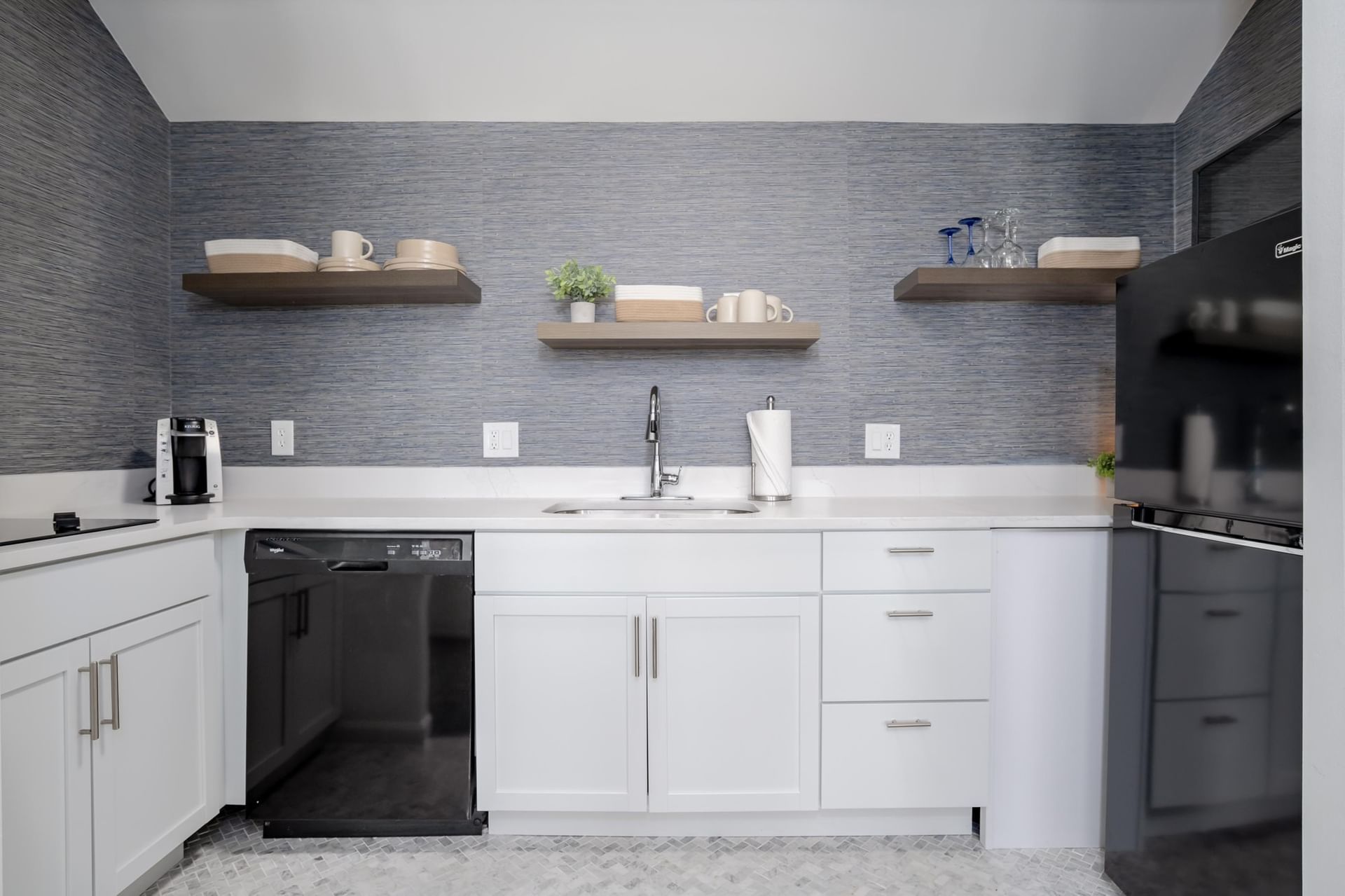 A small kitchenette with white cabinets, gray walls, and modern appliances.