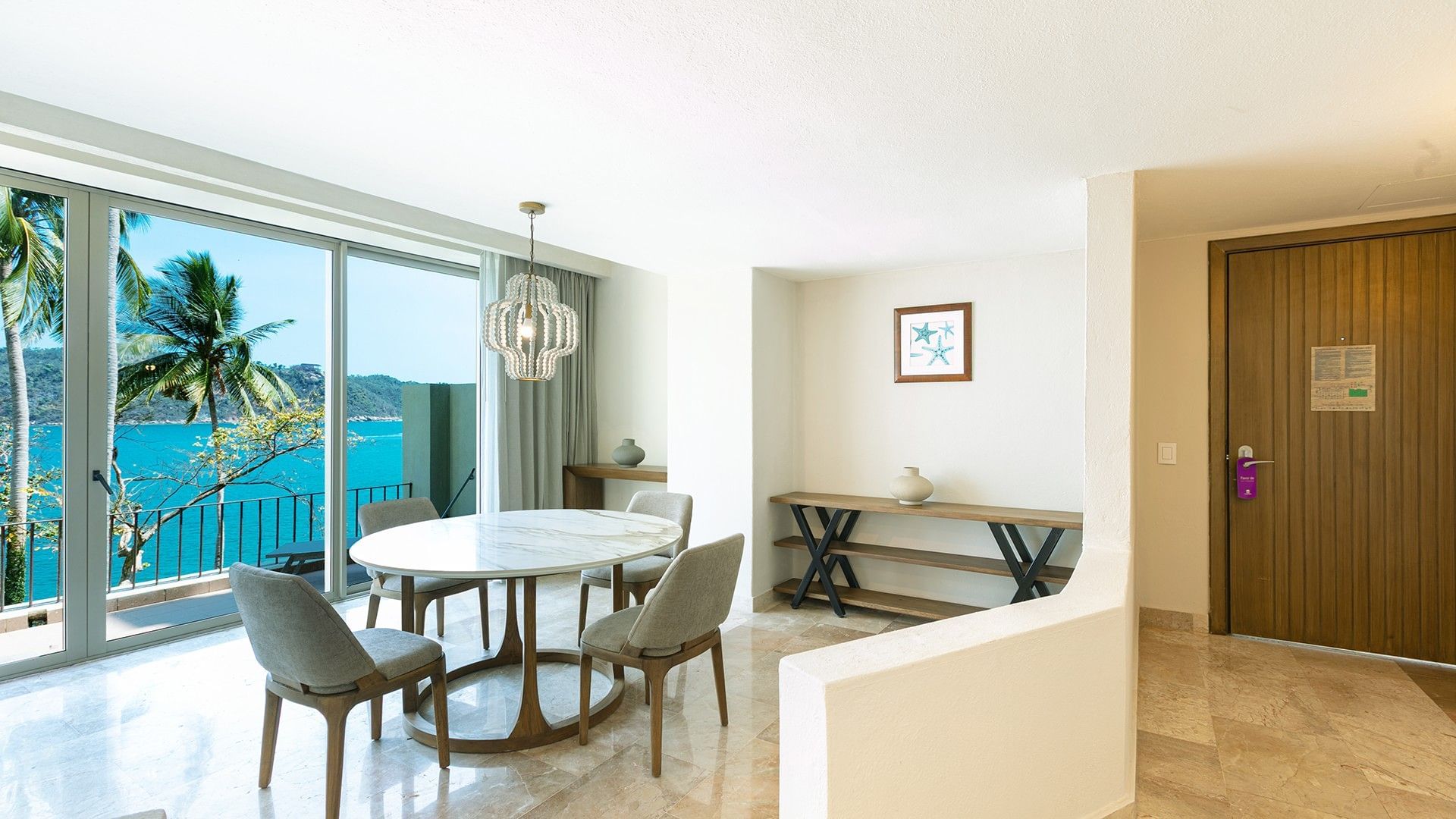 Dining area with a marble table and ocean view curtains in the King Junior Suite at Camino Real Acapulco Diamante