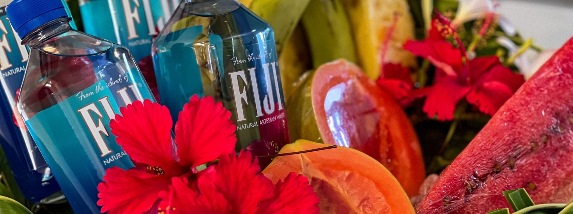 Bottles of Fiji water, fruit, and flowers in a woven basket at Tokatoka Resort - Fiji International Airport, Nadi.