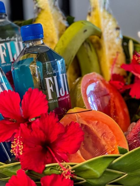 Bottles of Fiji water, fruit, and flowers in a woven basket at Tokatoka Resort - Fiji International Airport, Nadi.