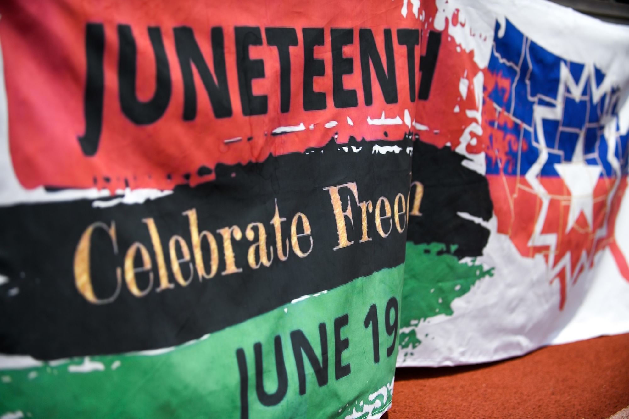 Flag with a red, black and green stripe that reads "Juneteenth," "Celebrate Freedom," and "June 19."