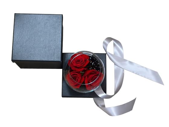 Black Box Containing a small glass vase with 3 rose buds and stones