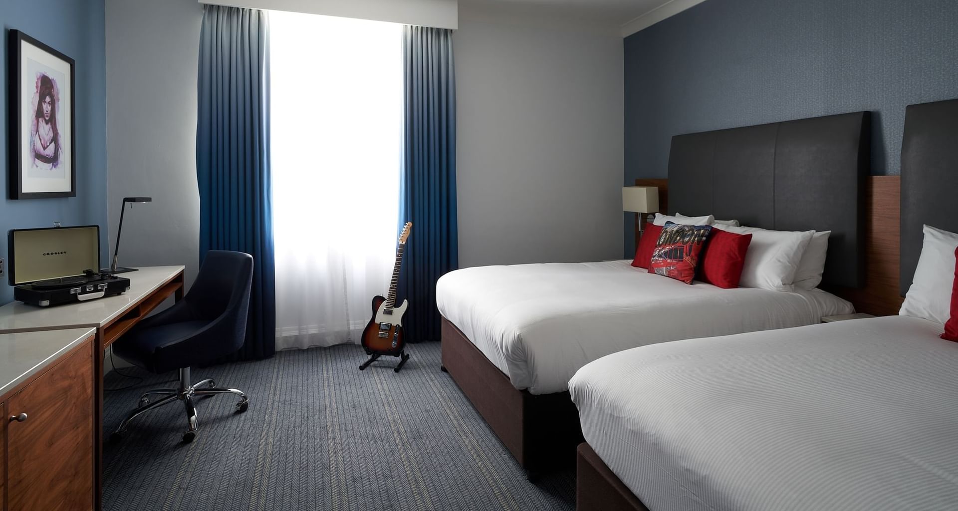 Queen beds, desk & guitar  in a room at Guoman Hotels