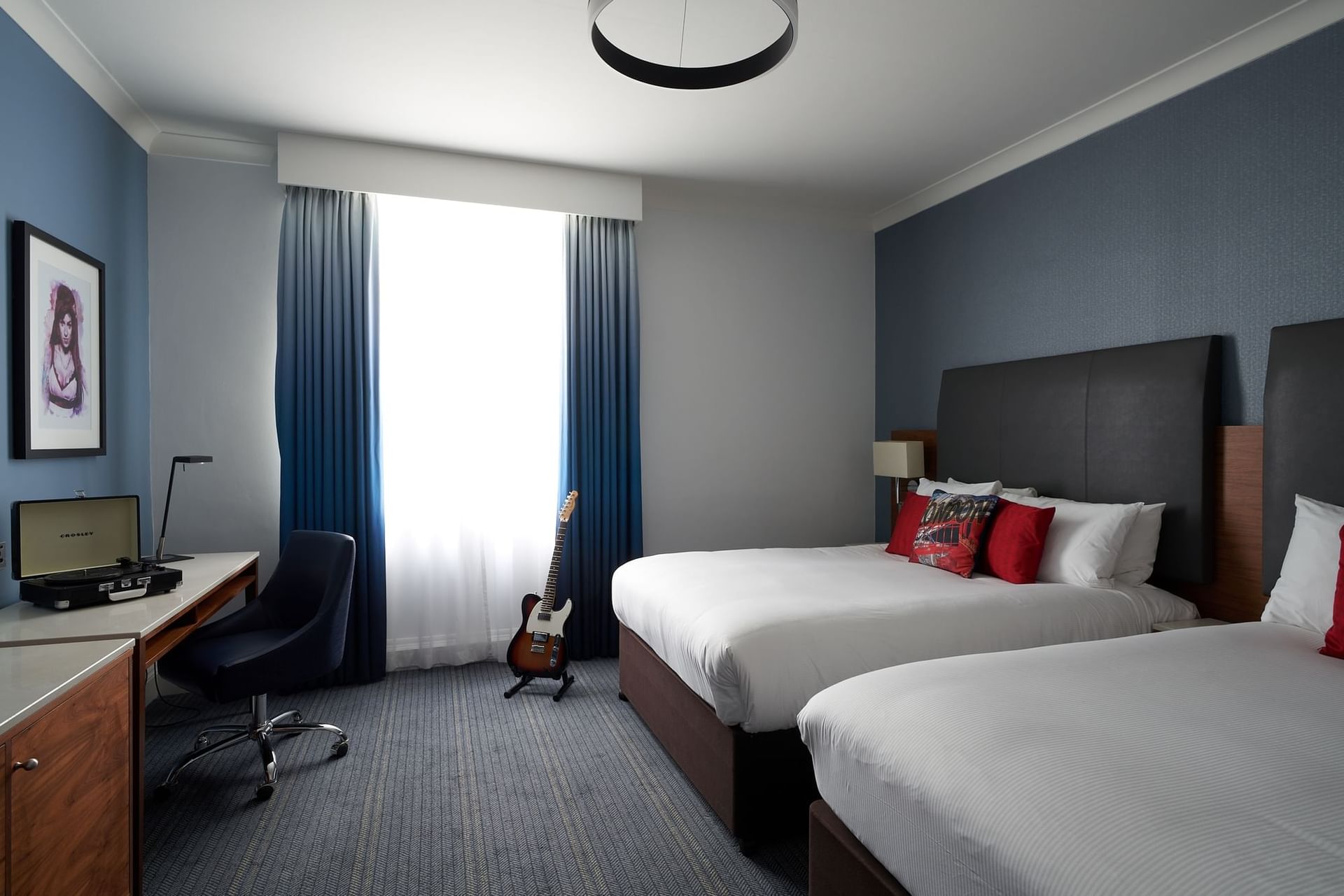 Queen beds, desk & guitar  in a room at Guoman Hotels