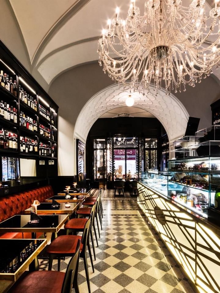 Elegant Diana’s Place with chandelier, wine shelf, and sleek seating on a checkered floor at The Independent