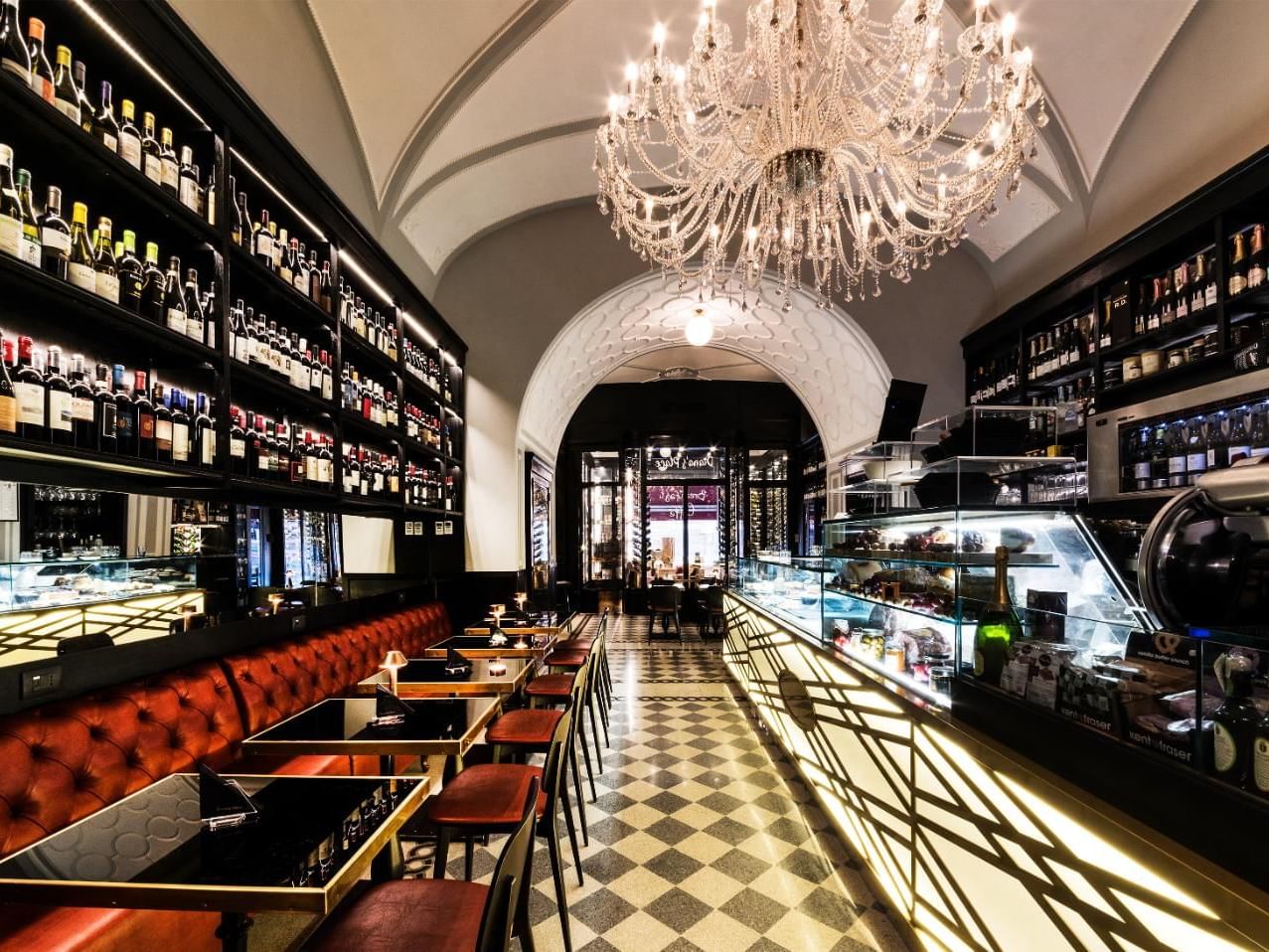Elegant Diana’s Place with chandelier, wine shelf, and sleek seating on a checkered floor at The Independent