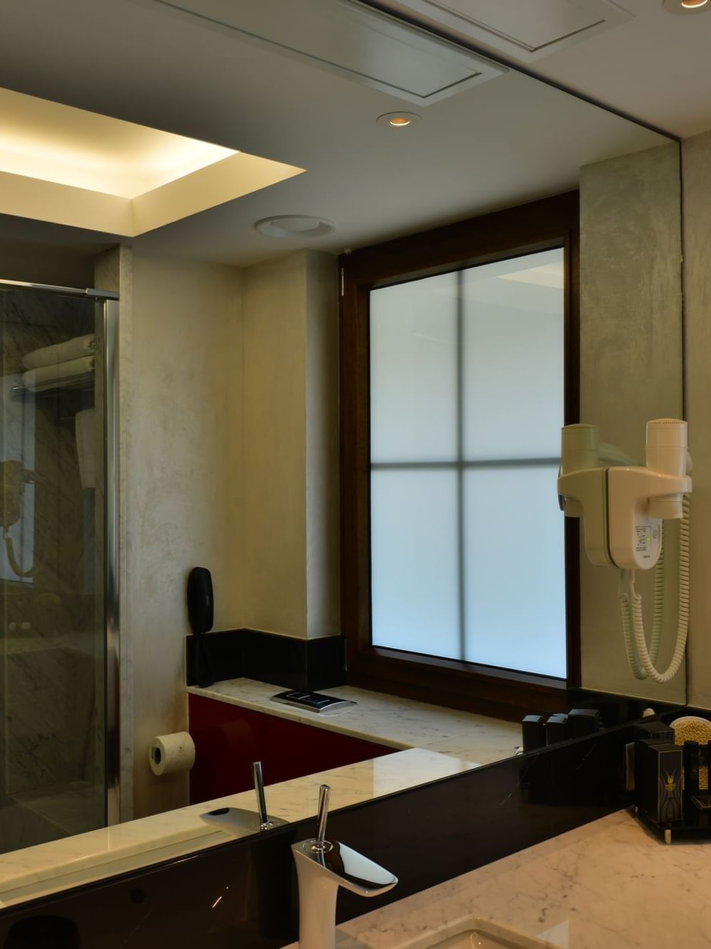 Modern bathroom with a marble vanity by a frosted window under a bright light in Executive Rooms at Warwick Ankara