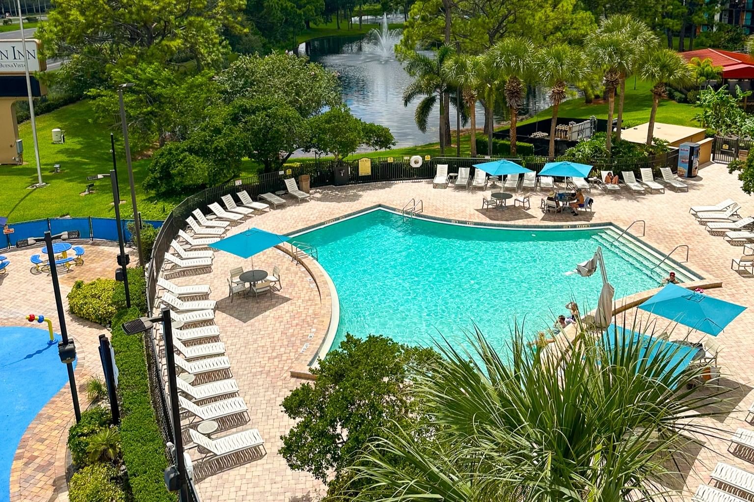 An overhead shot of one of the pools at Rosen Inn Lake Buena Vista in Orlando surrounded by lounge chairs and palm trees. 
