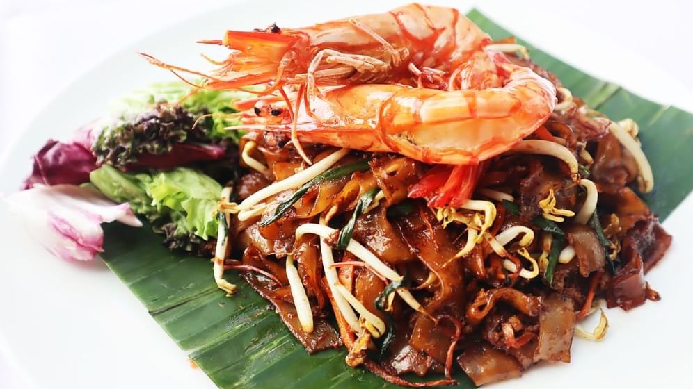 A plate of stir-fried noodles with shrimp and bean sprouts served on a banana leaf in Pendas Cafe at Sunway Hotel Big Box