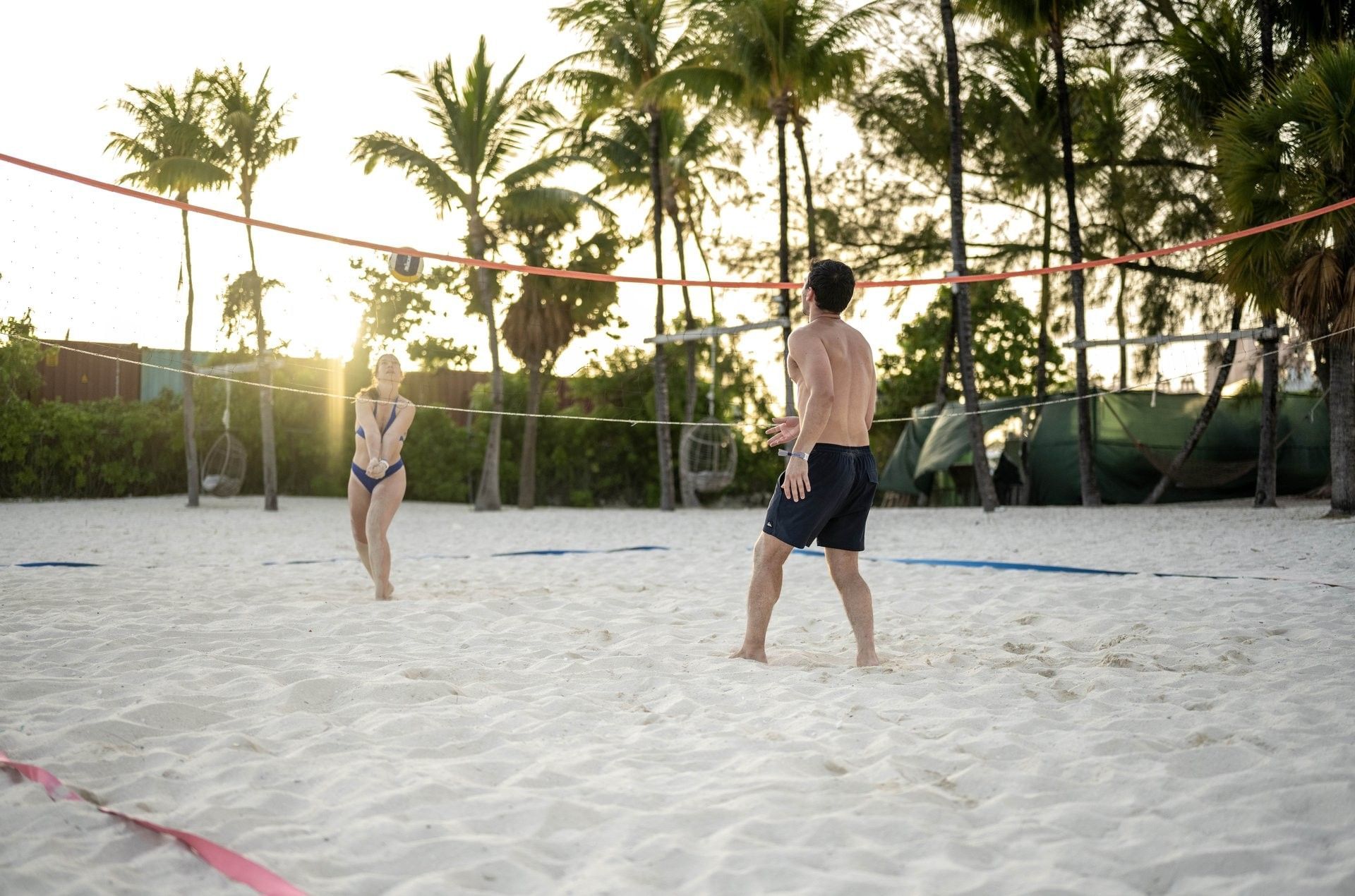 Volleyball by a net under palm trees surrounding guests on a sandy beach at Warwick Paradise Island Bahamas