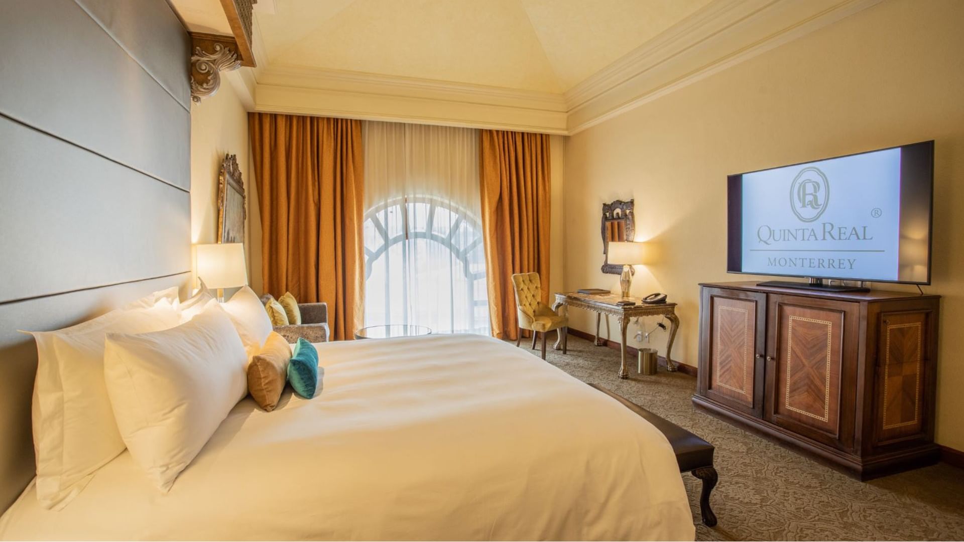King Presidential Suite with orange curtains, a marble desk, and a large flat-screen TV at Quinta Real Monterrey