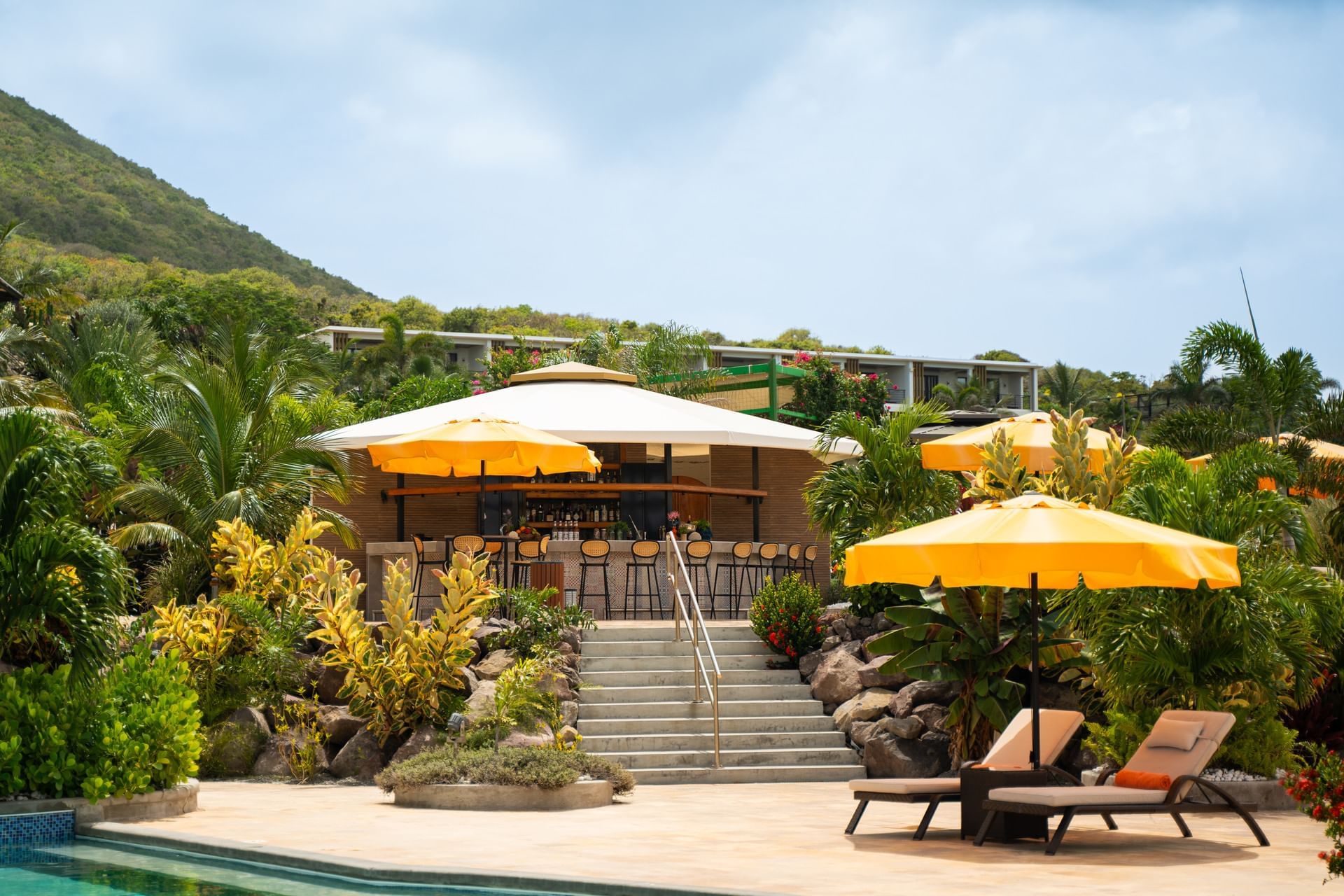 Buitenaanzicht van Pool Bar met gele parasols, omringd door weelderig groen bij Golden Rock Resort