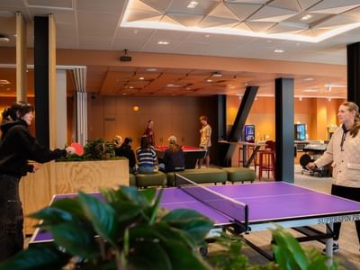 Guests playing table tennis in a modern recreation area with pool table and lounge seating at Tupuārangi