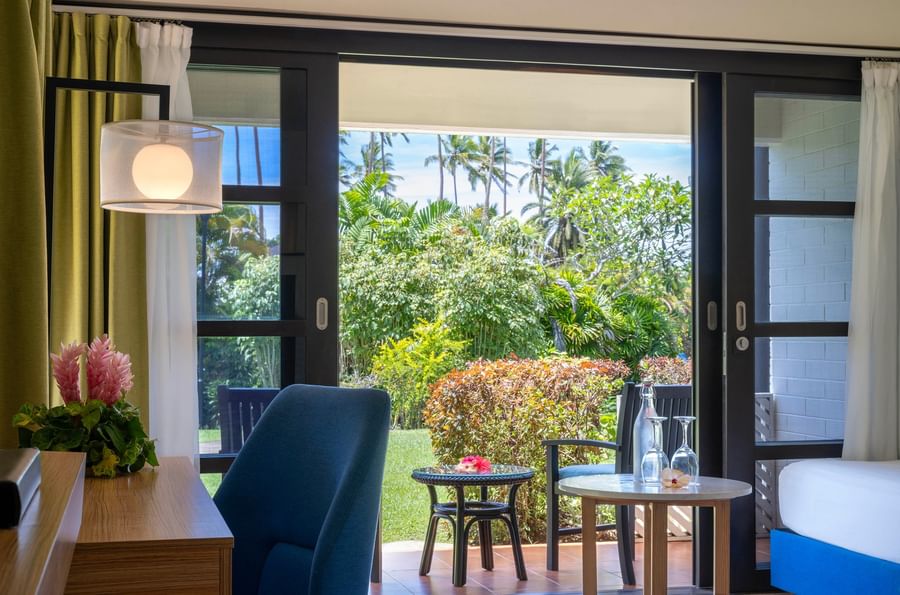 Modern hotel room with balcony view of lush tropical garden at The Naviti Resort.