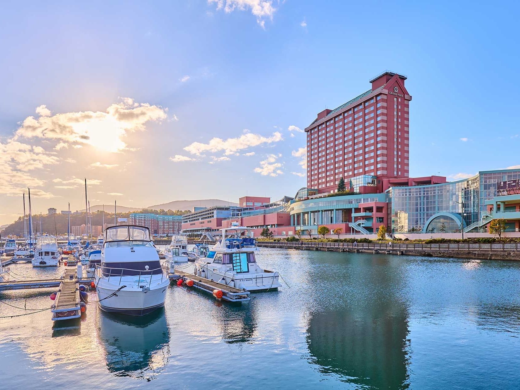 Distant exterior view of the Hotel & boats docked near Grand Park Otaru