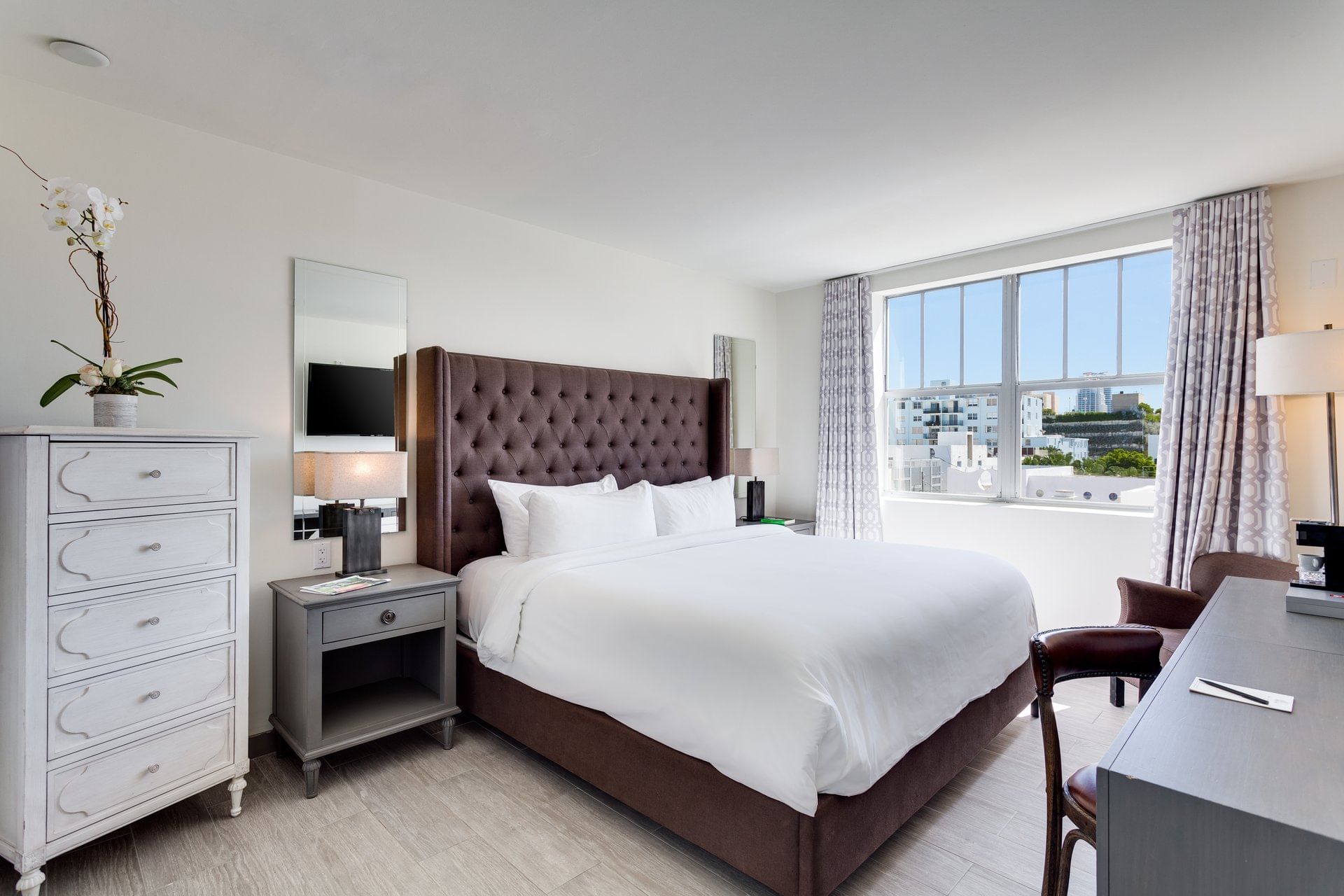 A wide view of a hotel room with a large bed, a window, and modern furniture.