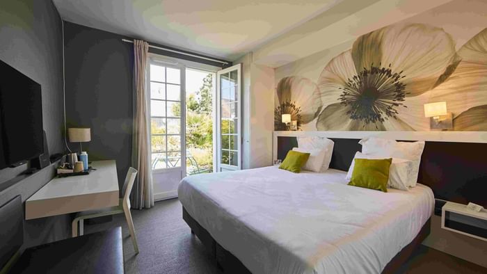 Chambre élégante avec lit, bureau et vue sur le jardin à Hôtel La Marébaudière