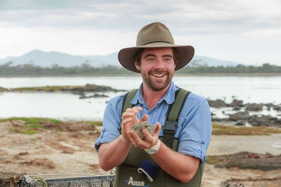 A tourist guide carrying stones on hands near Freycinet Lodge