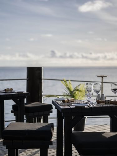 Outdoor tables with wine glasses by a rope railing in Wicked Walu at Warwick Fiji Resort and Spa