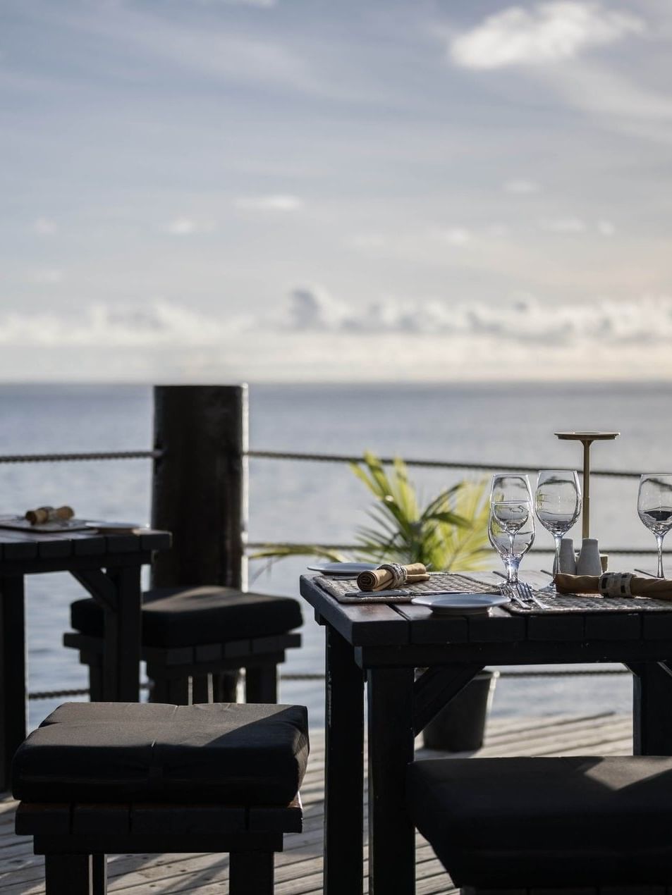 Outdoor tables with wine glasses by a rope railing in Wicked Walu at Warwick Fiji Resort and Spa