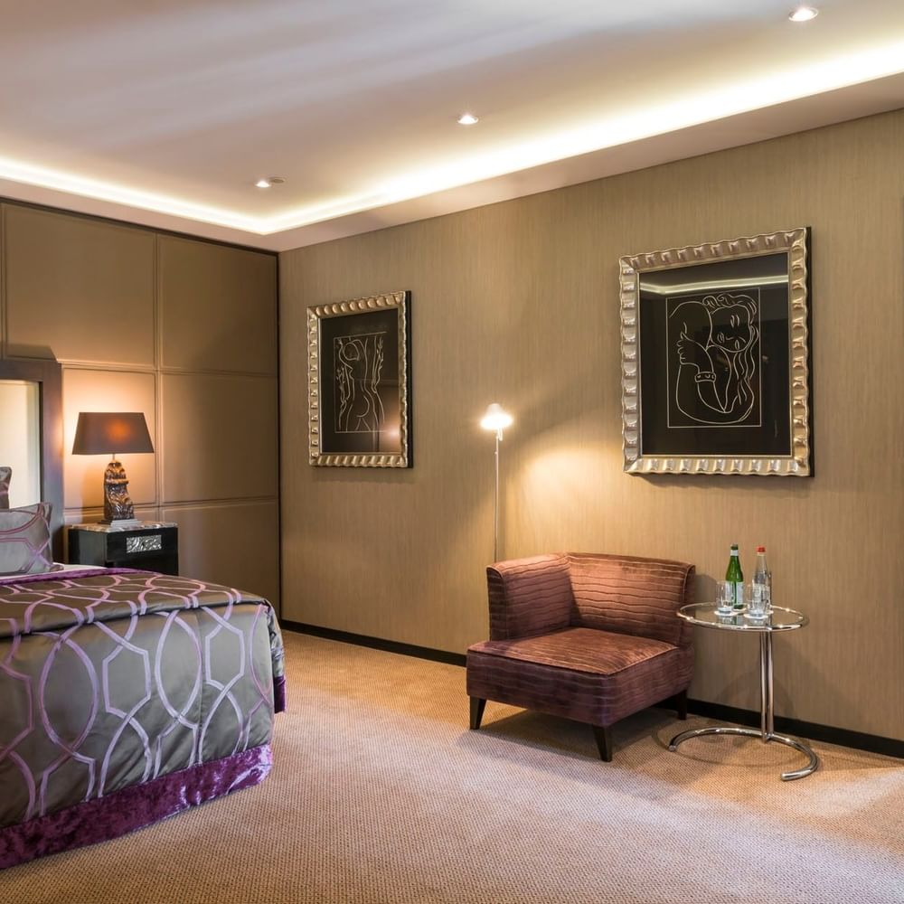 Bed with side table and couch by the doorway in the Grand-Place Suite at Warwick Grand Place Brussels